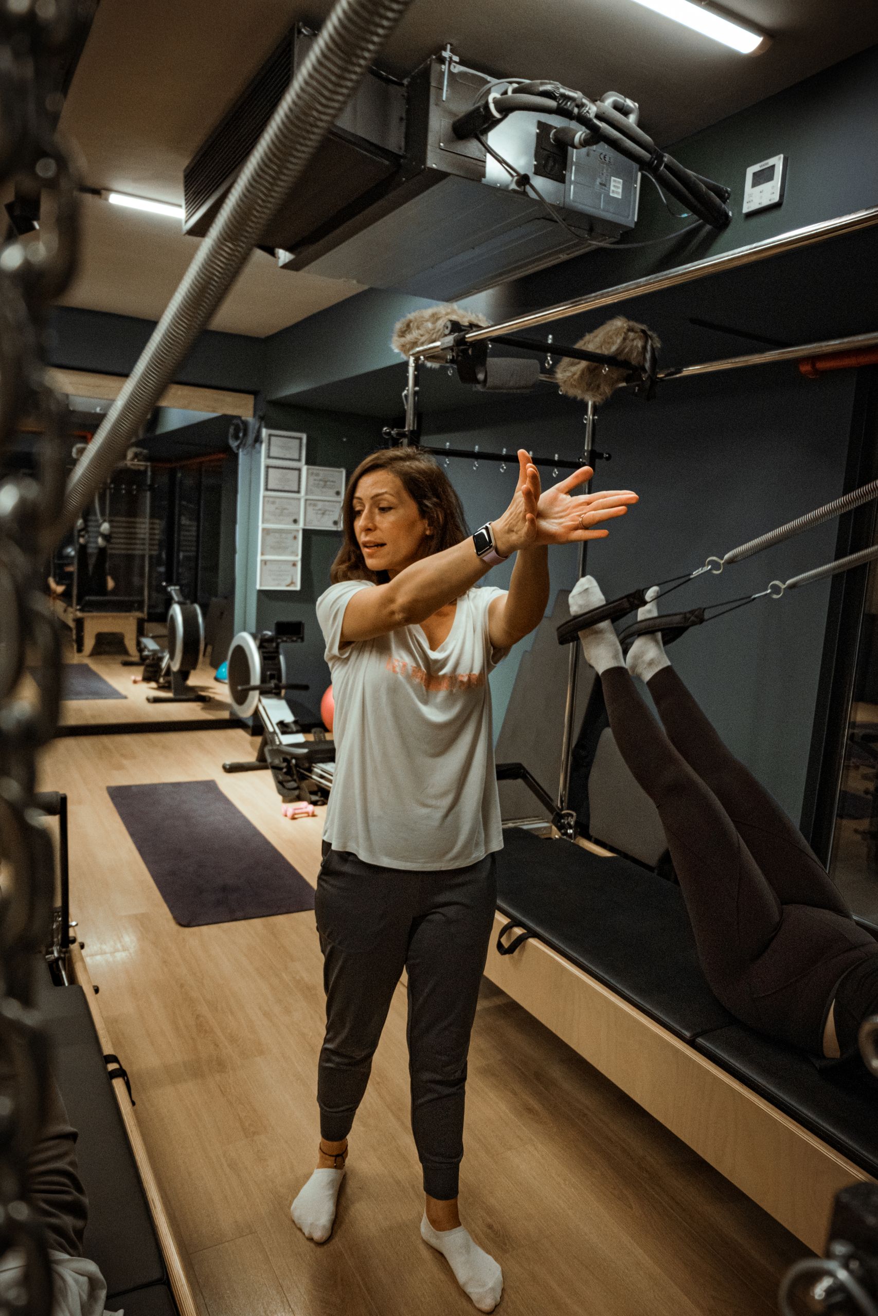A woman trainer guides a fitness session in a well-equipped gym.