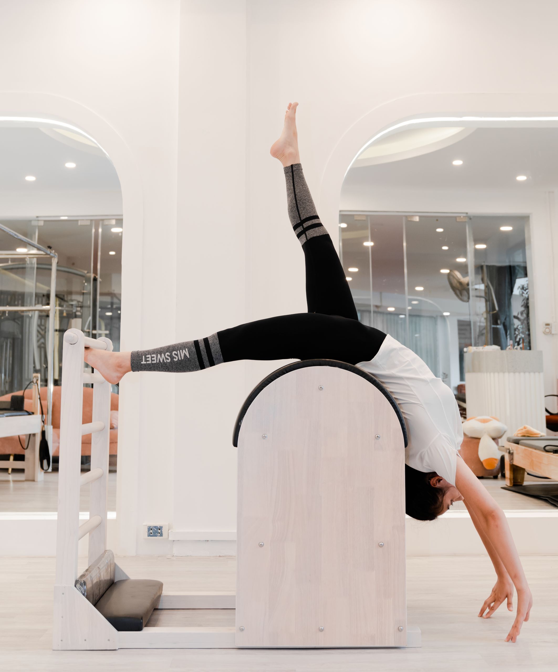 Woman engaged in pilates using specialized exercise equipment in a modern studio setting.